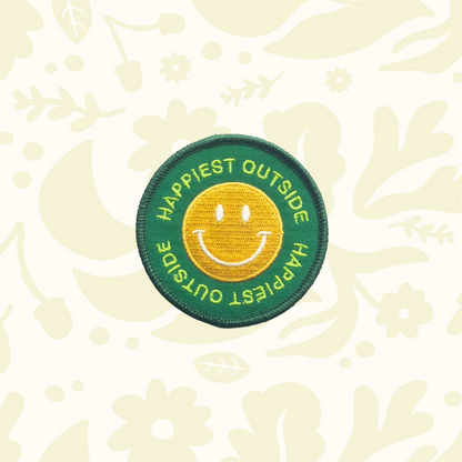 Forager Provisions LTD round embroidered iron-on patch with a yellow smiley face on a green background