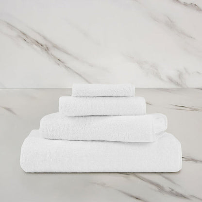 a white unito bath towel stacked on unito towels on a marbeled surface and background