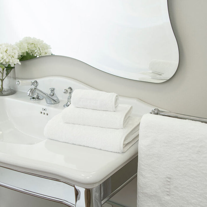 a white Unito Bath towel stacked on unito towles in a modern bathroom setting