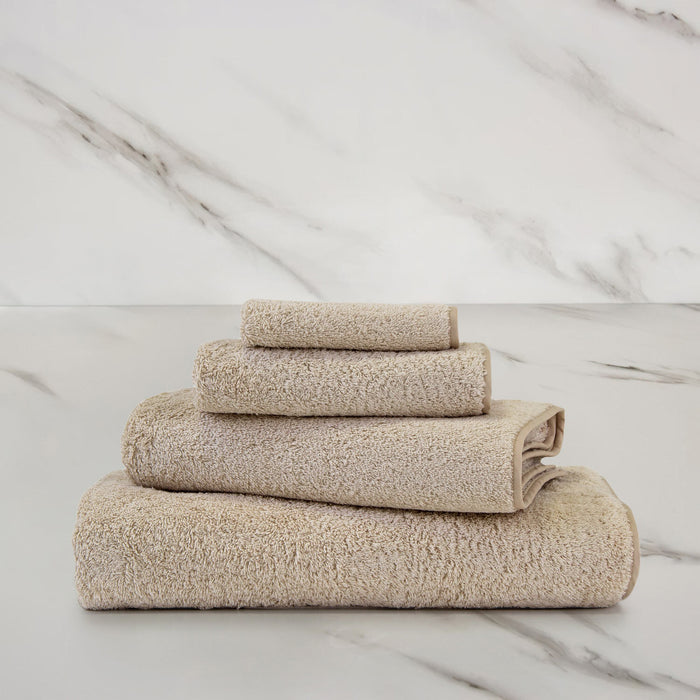 Unito Savage Beige Bath Towel on a marble surface
