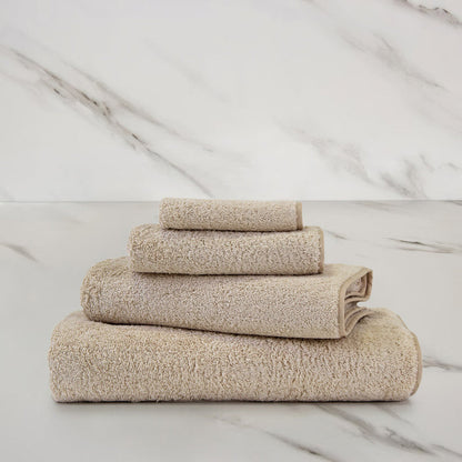 Unito Savage Beige Bath Towel on a marble surface