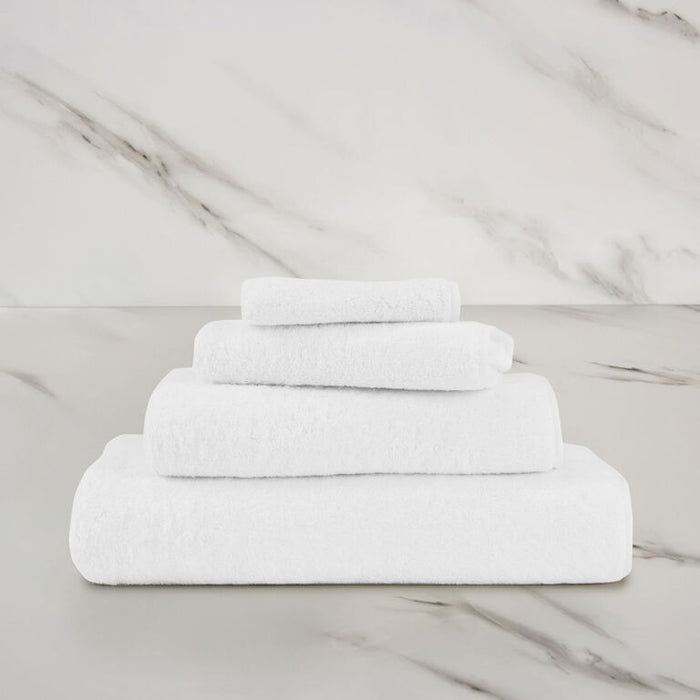 a white unito hand towel stacked on unito towels on a marbeled surface and background