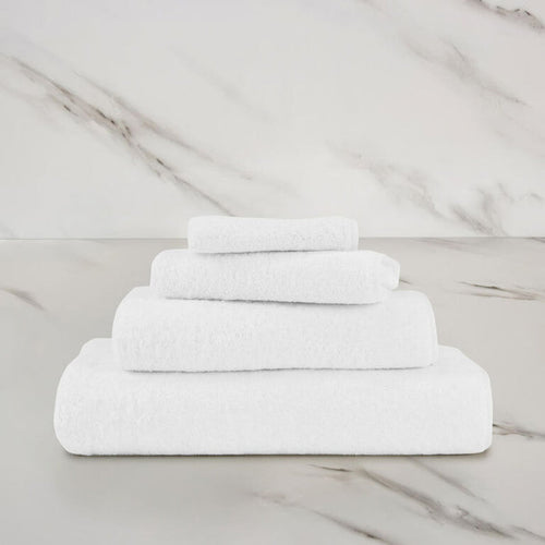 a white unito hand towel stacked on unito towels on a marbeled surface and background