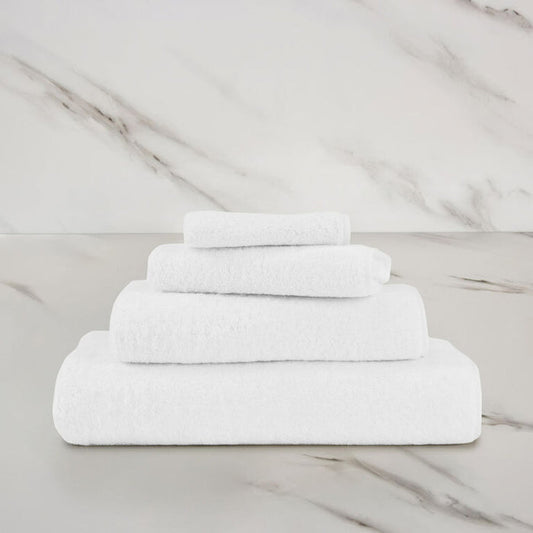 a white unito hand towel stacked on unito towels on a marbeled surface and background