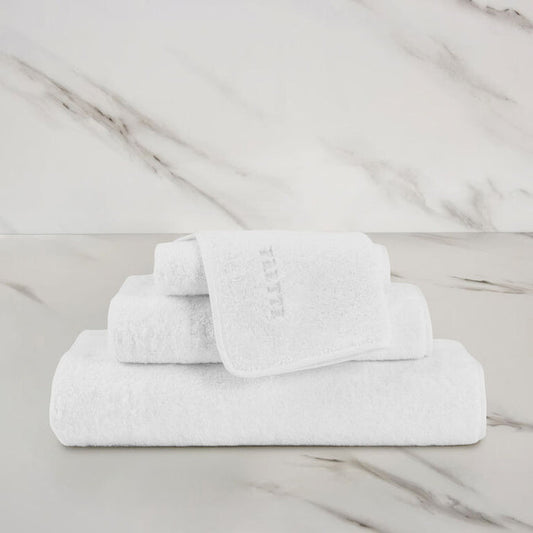 a white unito hand towel unfolded stacked on unito towels on a marbeled surface and background