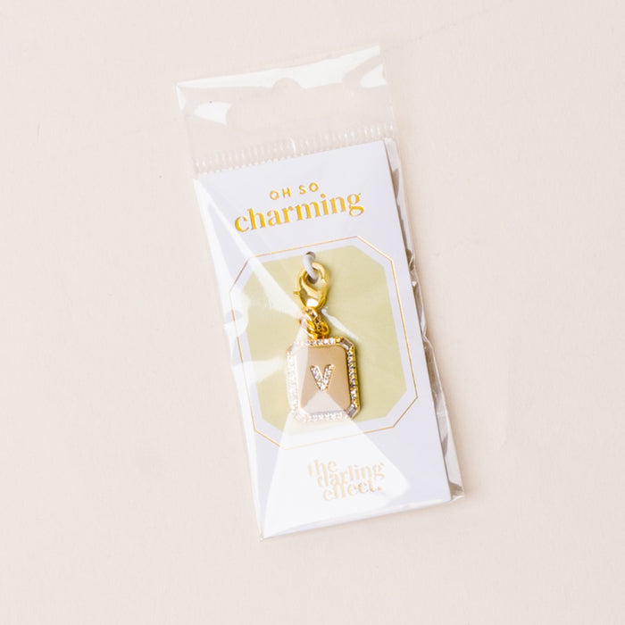 The-darling-effect's V Jewelry Charm Initial Letter Gold features a gold-plated initial with a lobster clasp, attached to an "OH SO charming" card and packaged in a clear sleeve—perfect for personalizing your jewelry.