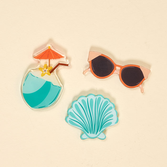 The Darling Effect's Vacation Vibes Little Magnet Set features three colorful acrylic magnets—a tropical drink, cat-eye sunglasses, and a blue seashell—perfect for adding decorative charm to your fridge.
