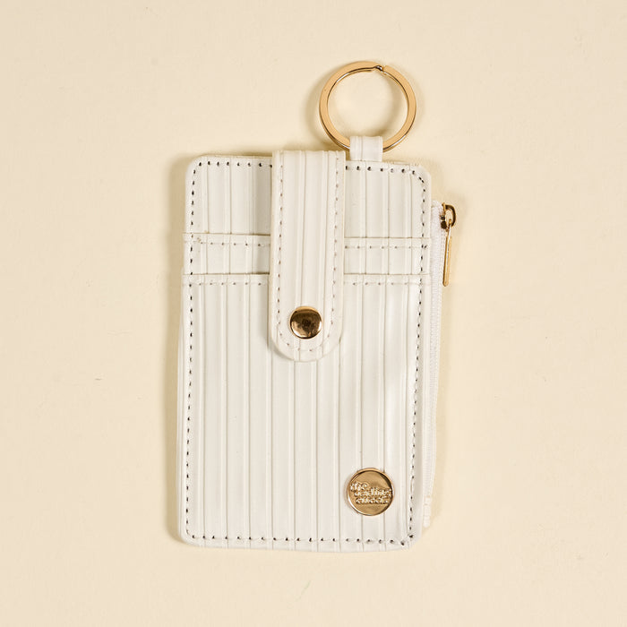 The Darling Effect’s White Ripple Ridge Keychain Wallet features a vertical design with gold accents, a snap button strap, top keyring, side zippered coin holder, and small round logo at the bottom right on a beige background.
