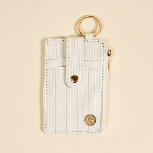 The Darling Effect’s White Ripple Ridge Keychain Wallet features a vertical design with gold accents, a snap button strap, top keyring, side zippered coin holder, and small round logo at the bottom right on a beige background.