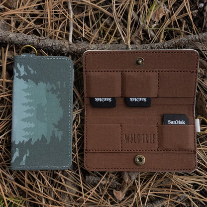 Wildtree Forest Friend SD/Switch card holders on pine needles, one open showing 4 SanDisk cards, one closed.