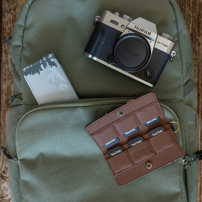 Green backpack with Fujifilm camera, notebook, Wildtree Forest Friend card holder, six SanDisk memory cards inside.