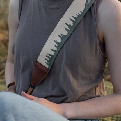 Woman in gray sleeveless top with Wildtree Landscape Camera Strap featuring trees & mountains, draped over her shoulder.