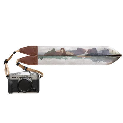 Forager Provisions LTD Wildtree camera strap featuring a landscape print with brown synthetic leather ends on a camera.