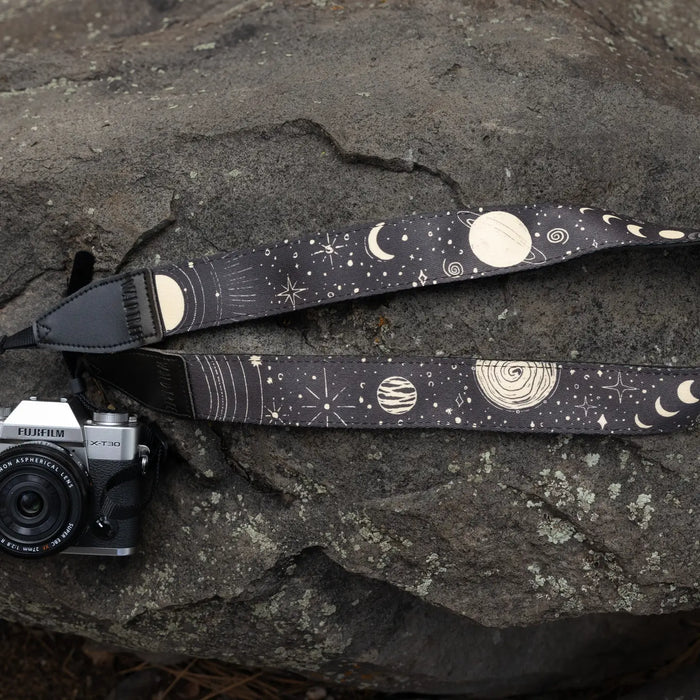 Fujifilm camera with stylish Wildtree Sun & Moon Camera Strap placed on large gray rock, perfect outdoor photography gear setup.
